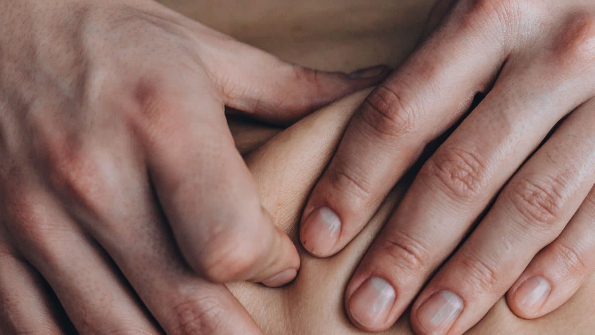 Gros plan sur des mains exerçant une pression appuyée des pouces le long du dos